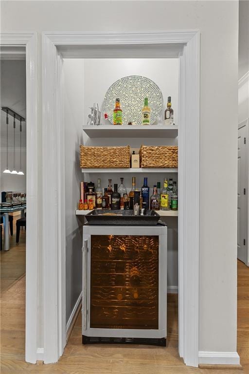 bar with wine cooler, wood finished floors, and a bar