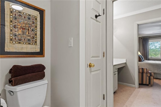 bathroom with toilet, baseboards, vanity, and crown molding