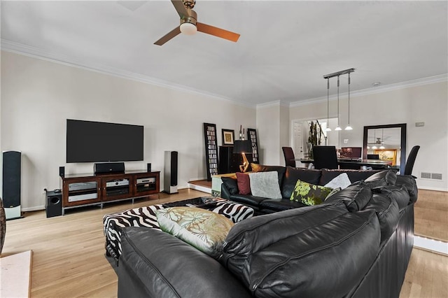 living area with a ceiling fan, crown molding, light wood-style floors, baseboards, and visible vents
