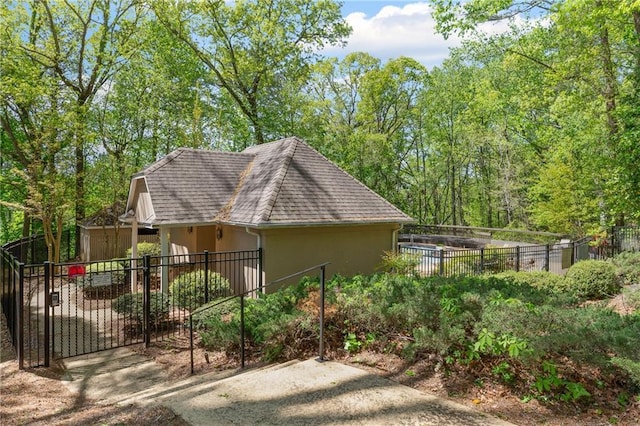 view of side of property featuring a shingled roof, stucco siding, and fence