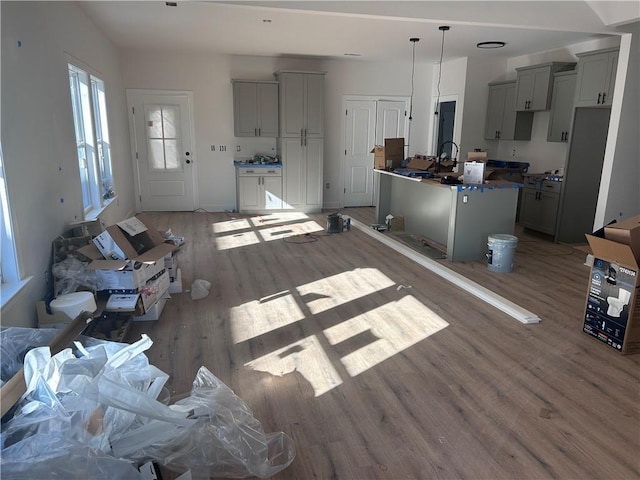 kitchen featuring gray cabinetry, pendant lighting, a center island, sink, and hardwood / wood-style flooring