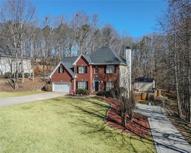 view of front facade featuring a front yard, brick siding, driveway, and a chimney