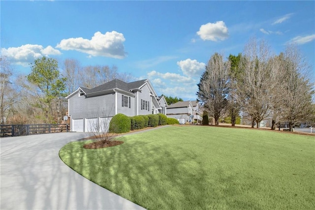 view of property exterior featuring an attached garage, driveway, fence, and a lawn