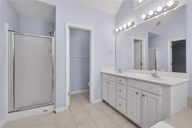 bathroom featuring double vanity, lofted ceiling, tile patterned floors, a shower stall, and a sink