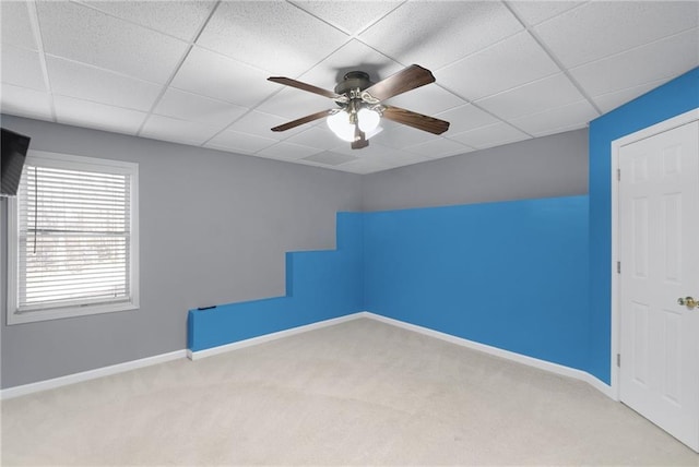 empty room with ceiling fan, a drop ceiling, carpet flooring, and baseboards