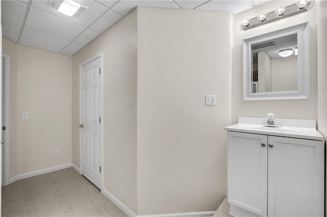 bathroom with a paneled ceiling, baseboards, and vanity