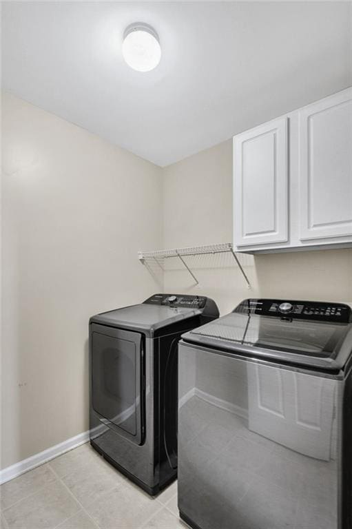 laundry area featuring cabinet space, baseboards, washer and clothes dryer, and light tile patterned flooring