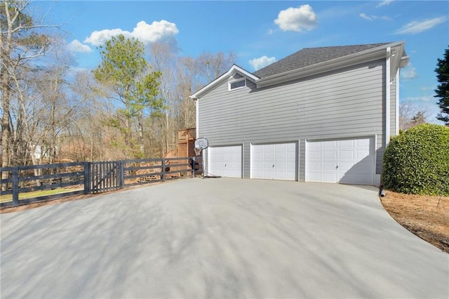 view of side of property with driveway, a garage, and fence