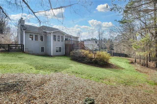 exterior space featuring a lawn, a chimney, stairway, fence, and a deck