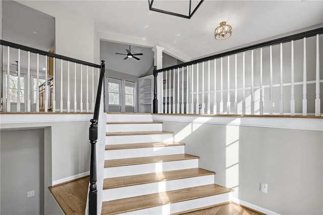 stairway featuring lofted ceiling, baseboards, and a ceiling fan