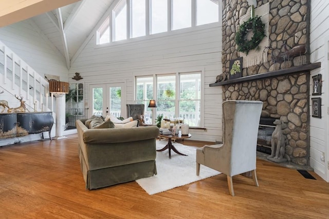 328 Black Ankle Creek Rd, Cherry Log, GA 30522 - living room featuring french doors, a stone fireplace, wood walls, beam ceiling, and light hardwood / wood-style floors