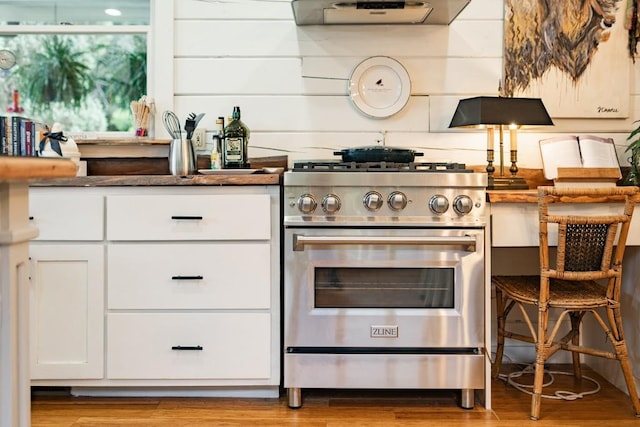 328 Black Ankle Creek Rd, Cherry Log, GA 30522 - kitchen with high end stainless steel range oven, extractor fan, white cabinetry, and light hardwood / wood-style floors
