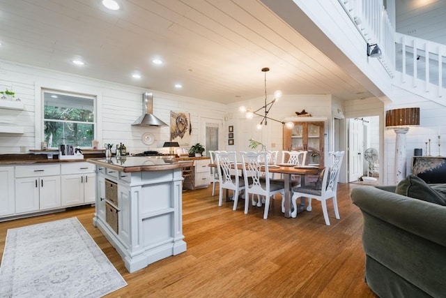 328 Black Ankle Creek Rd, Cherry Log, GA 30522 - kitchen featuring wall chimney exhaust hood, white cabinetry, a kitchen island, pendant lighting, and light hardwood / wood-style floors