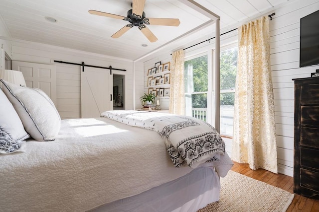 328 Black Ankle Creek Rd, Cherry Log, GA 30522 - bedroom featuring hardwood / wood-style flooring, wooden walls, a barn door, and ceiling fan