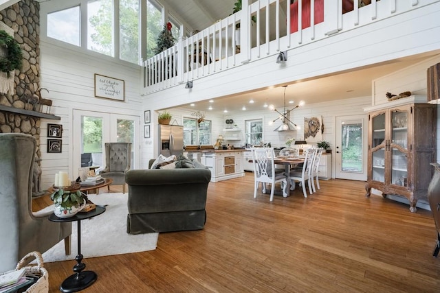 328 Black Ankle Creek Rd, Cherry Log, GA 30522 - living room featuring a towering ceiling, light hardwood / wood-style flooring, wooden walls, and french doors