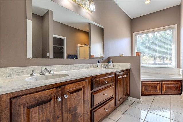 bathroom with a garden tub, double vanity, a sink, and tile patterned floors