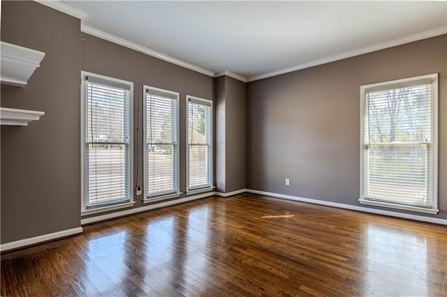 spare room featuring ornamental molding, baseboards, and wood finished floors