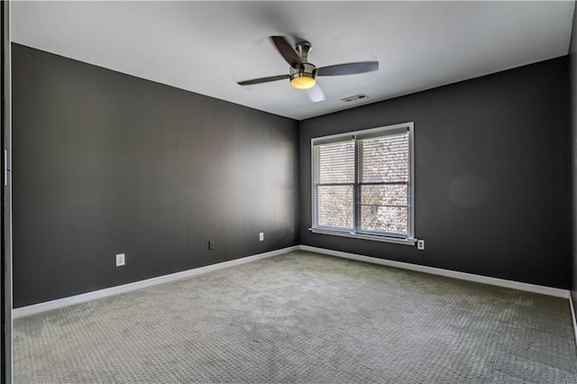 carpeted spare room with a ceiling fan, visible vents, and baseboards