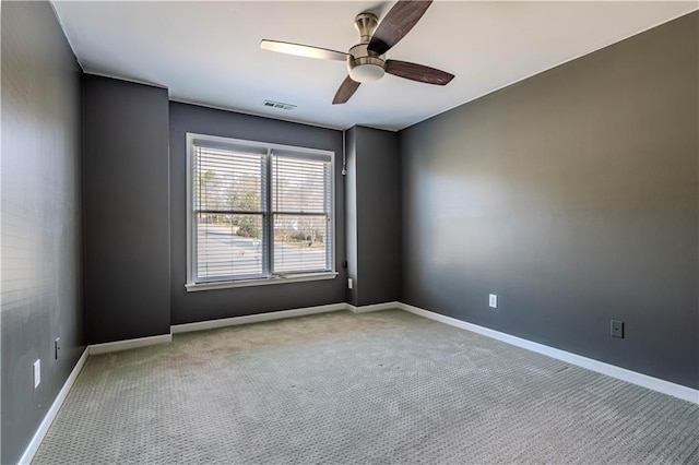 carpeted spare room featuring baseboards, visible vents, and a ceiling fan