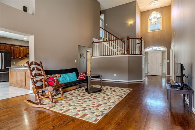 living area with wood-type flooring, stairway, and baseboards