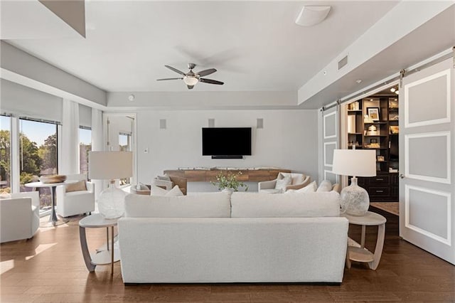 living room with hardwood / wood-style floors, ceiling fan, and a barn door