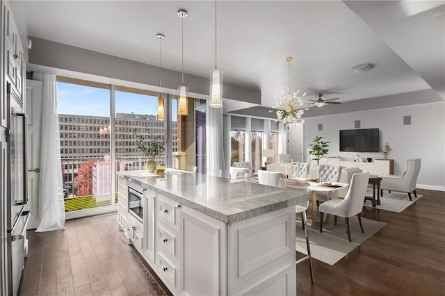 kitchen featuring white cabinetry, light stone counters, dark hardwood / wood-style flooring, decorative light fixtures, and ceiling fan with notable chandelier