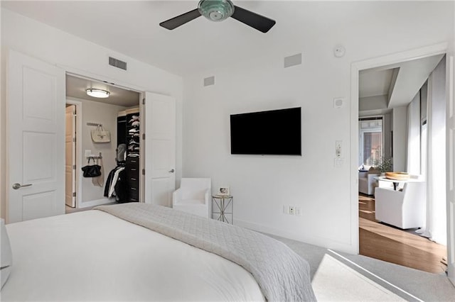 carpeted bedroom with a walk in closet, a closet, and ceiling fan