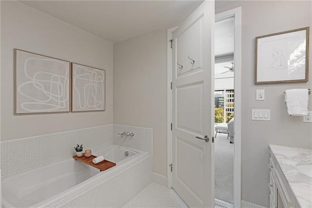 bathroom with tile patterned floors, tiled tub, and vanity