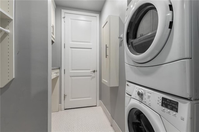 laundry area featuring light tile patterned flooring and stacked washer and dryer