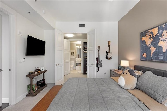 bedroom featuring ensuite bathroom and light colored carpet