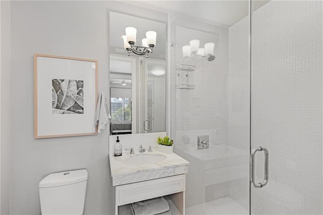 bathroom with toilet, vanity, a shower with shower door, and an inviting chandelier