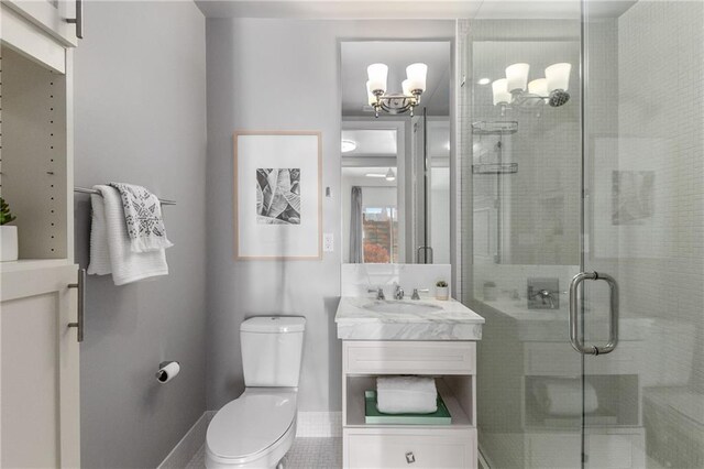 bathroom with an enclosed shower, vanity, an inviting chandelier, tile patterned flooring, and toilet