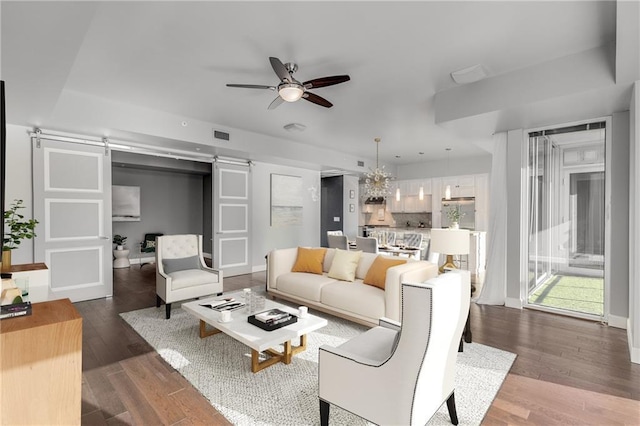 living room featuring hardwood / wood-style floors, a barn door, and ceiling fan