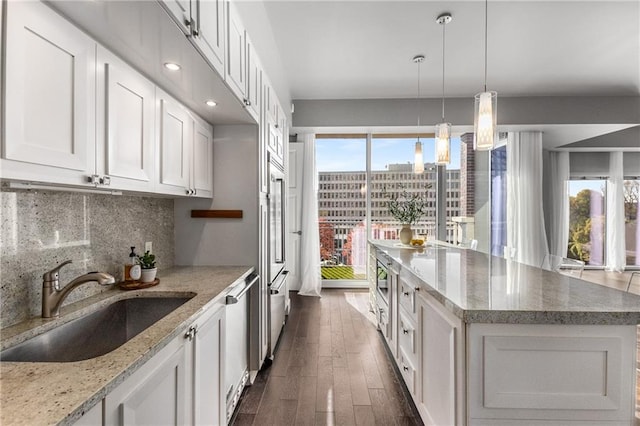 kitchen with a healthy amount of sunlight, light stone countertops, white cabinetry, and dark wood-type flooring