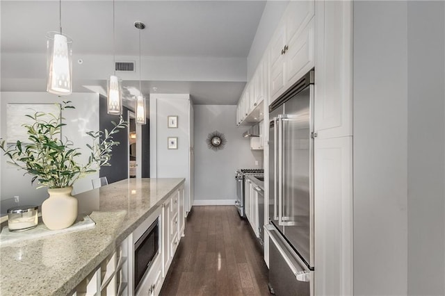 kitchen featuring light stone counters, dark wood-type flooring, built in appliances, white cabinetry, and hanging light fixtures