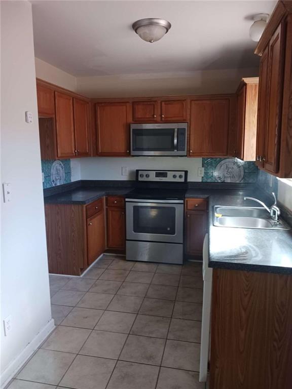 kitchen with stainless steel appliances, tasteful backsplash, light tile flooring, and sink