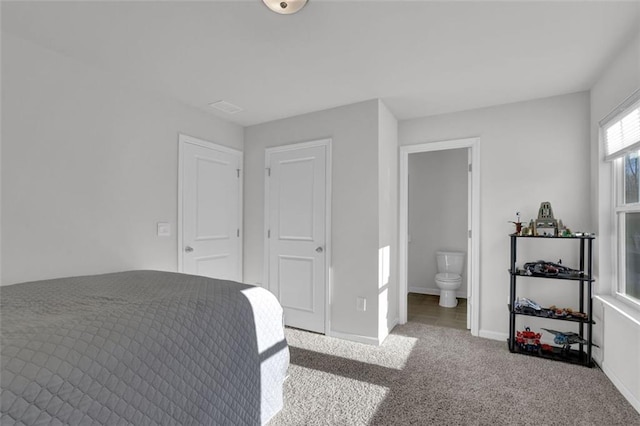 carpeted bedroom with ensuite bath and a closet