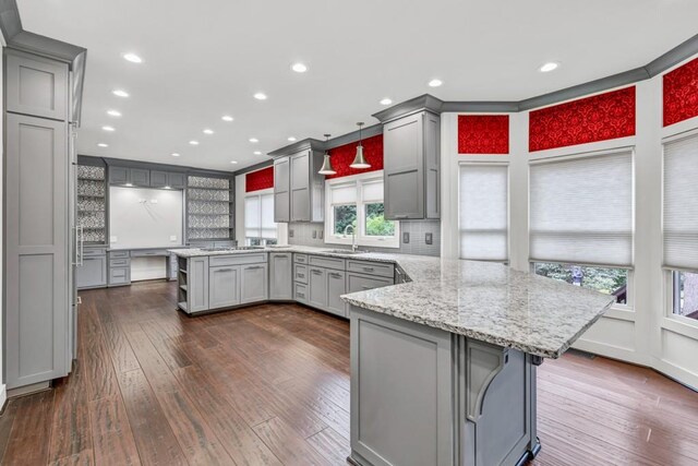 kitchen featuring gray cabinetry, a sink, a peninsula, and dark wood finished floors