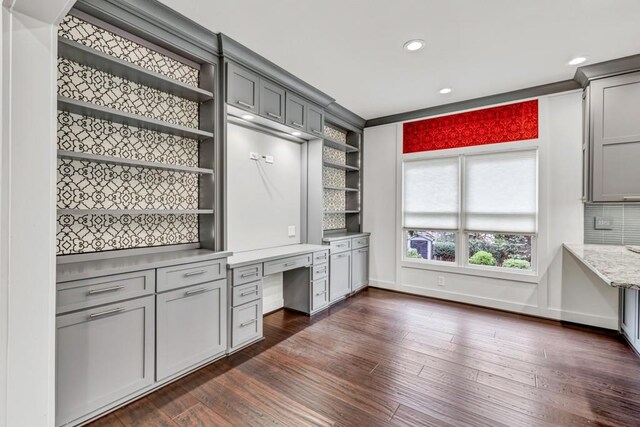 kitchen with built in desk, dark wood-style flooring, open shelves, and gray cabinets