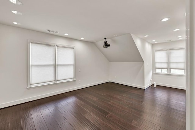 additional living space with vaulted ceiling, visible vents, baseboards, and wood-type flooring