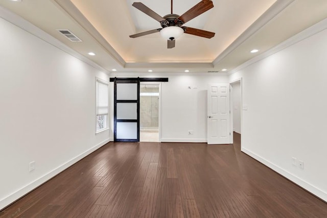 spare room with a ceiling fan, a raised ceiling, baseboards, visible vents, and dark wood-type flooring