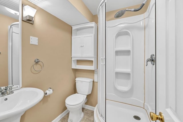 full bathroom featuring a shower stall, baseboards, toilet, a sink, and tile patterned flooring