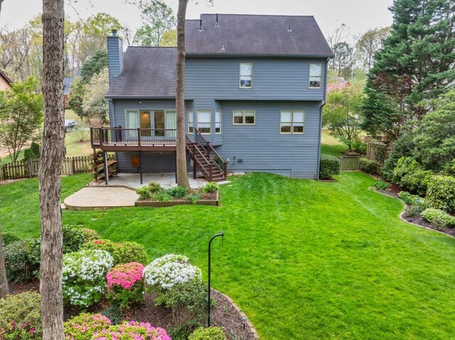 rear view of property with fence, a deck, a patio, and a yard