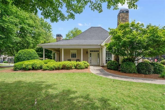 view of front facade featuring a chimney, a front yard, and stucco siding