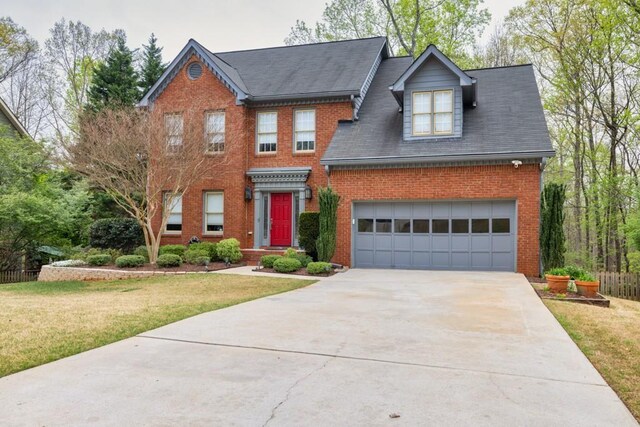 view of front facade featuring concrete driveway, fence, a front yard, brick siding, and a garage