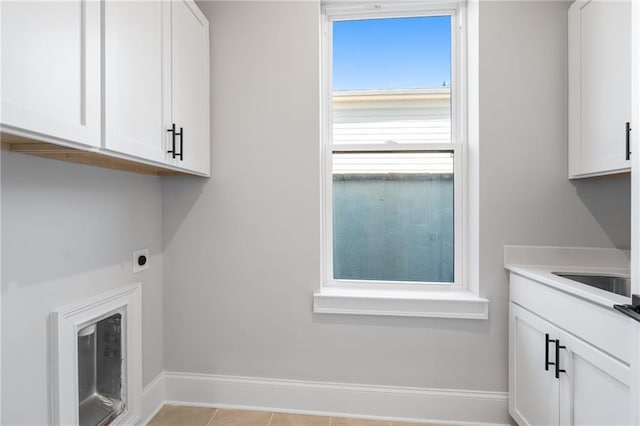 clothes washing area featuring hookup for an electric dryer, a sink, baseboards, cabinet space, and tile patterned floors