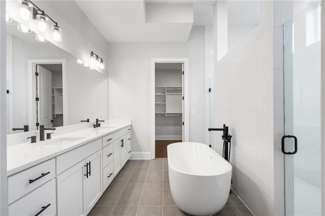 bathroom with double vanity, tile patterned flooring, a walk in closet, and a sink