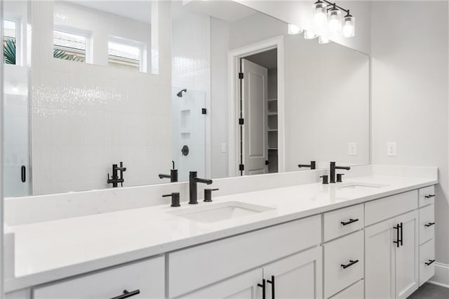 full bath with double vanity, tiled shower, and a sink