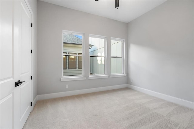 empty room featuring light carpet, baseboards, and a ceiling fan