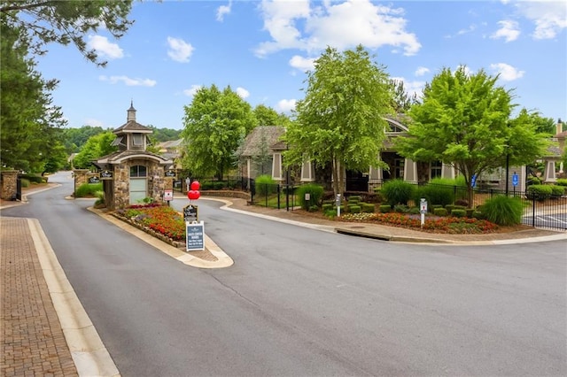 view of road with sidewalks, a gated entry, and curbs